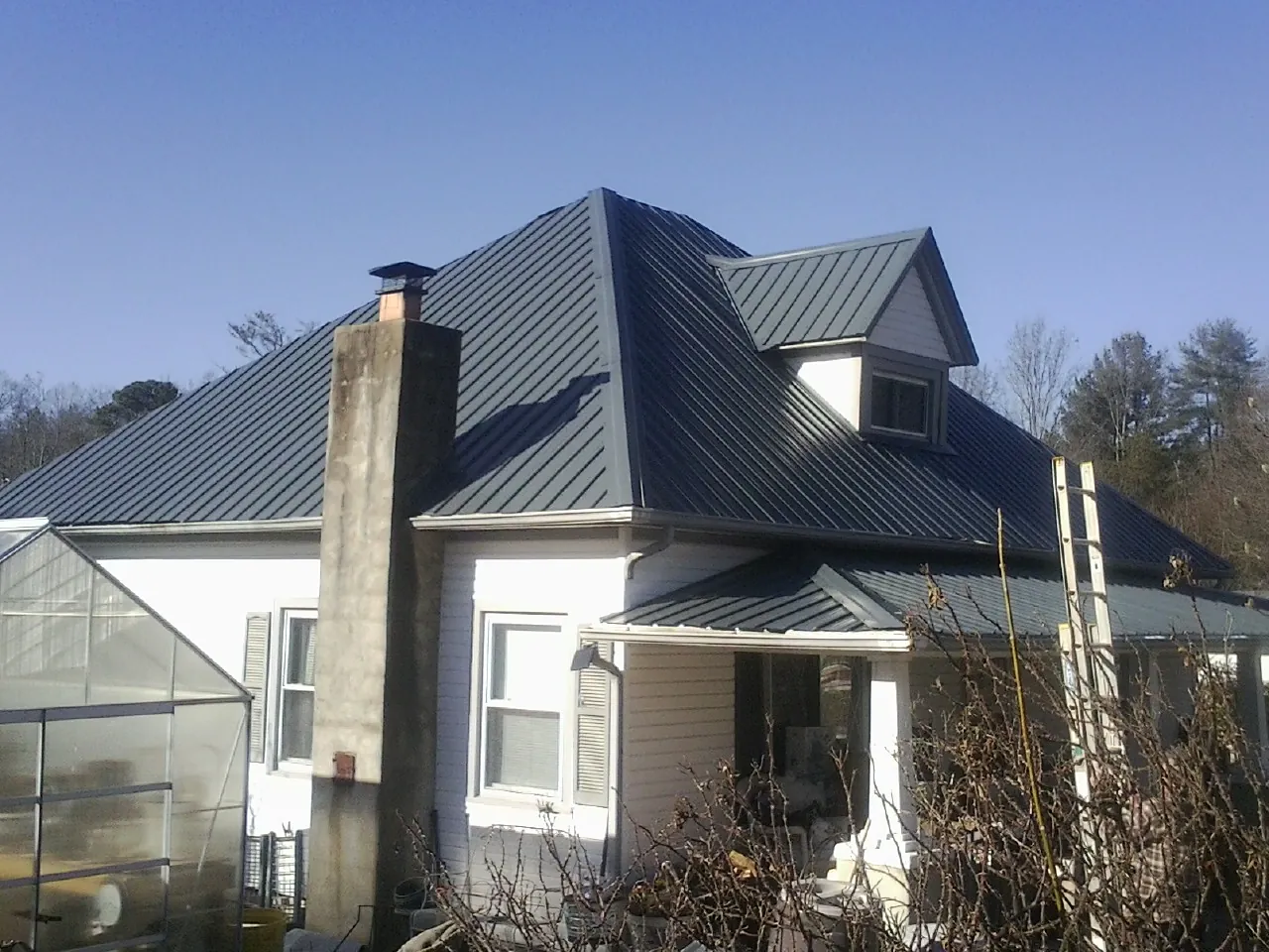 Dark blue standing seam metal roof on a white farmhouse with dormer — Slate & Tile Roof Repair by Roofing Brothers in Scotland