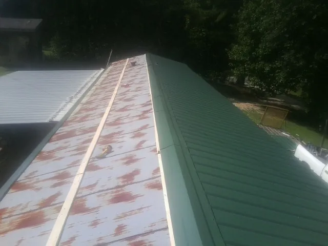 Old rusted panels beside newly installed green metal roofing — Wind Damage Roof Repair by Roofing Brothers in Scotland