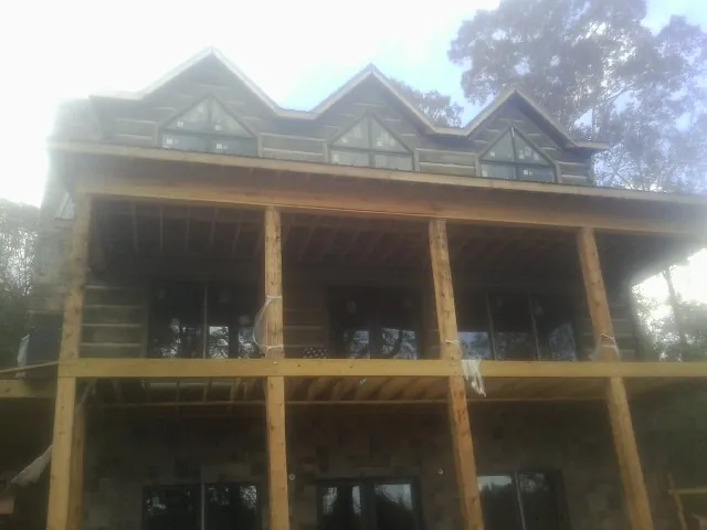 Dormers and porch framing on a large log home under construction — Roof Coating work by our crew in Scotland