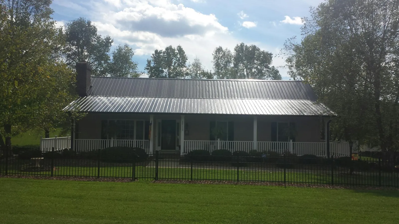 Gray metal roof on a brick ranch with a full width front porch — Gutter Guard Installation work by our crew in Scotland